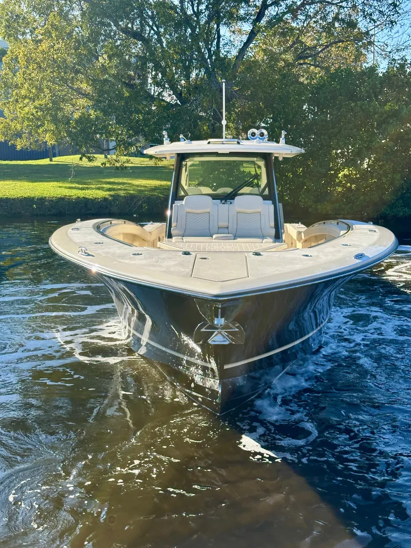 Slide: The Image of 2025 Scout 425 LXF boat cruising on a sunny day in a scenic waterway. - 4