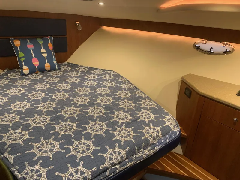 Slide: The Image of 2012 Tiara Yachts 3100 Coronet cabin with nautical-themed bedding and cozy interior lighting. - 11