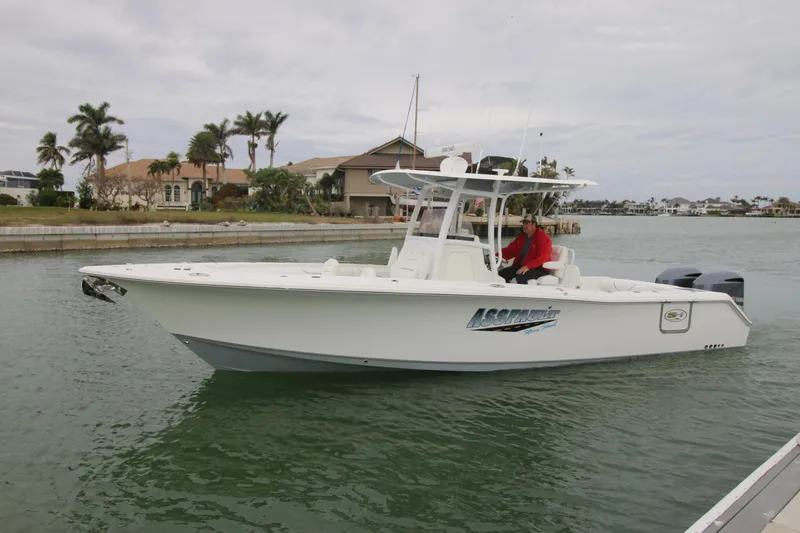 Slide: The Image of 2016 Sea Hunt Gamefish 30 boat on water, with palm trees and houses in the background. - 0