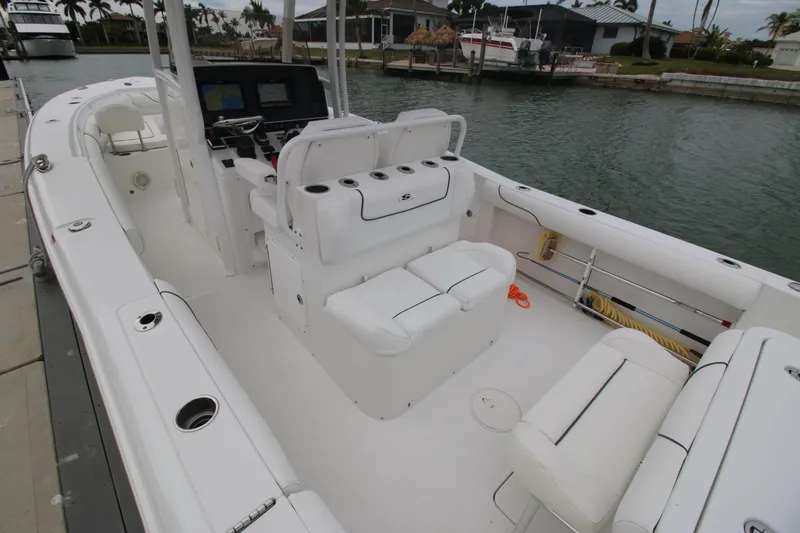 Slide: The Image of 2016 Sea Hunt Gamefish 30 boat interior with seating and control panel, docked by the water. - 17