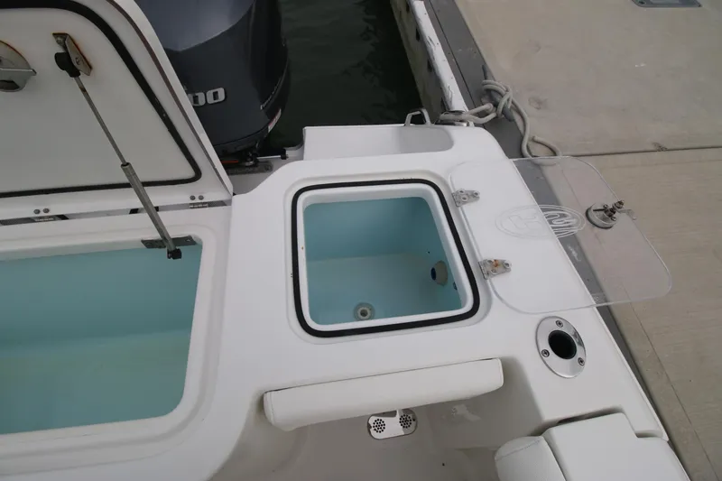 Slide: The Image of 2016 Sea Hunt Gamefish 30 boat with open storage compartments and motor at dock. - 22