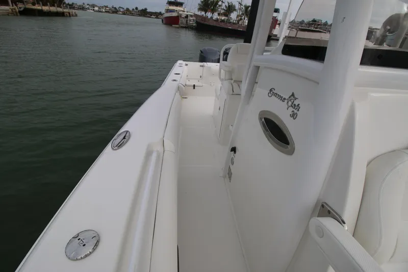 Slide: The Image of 2016 Sea Hunt Gamefish 30 boat docked, showcasing sleek white deck and spacious layout. - 34