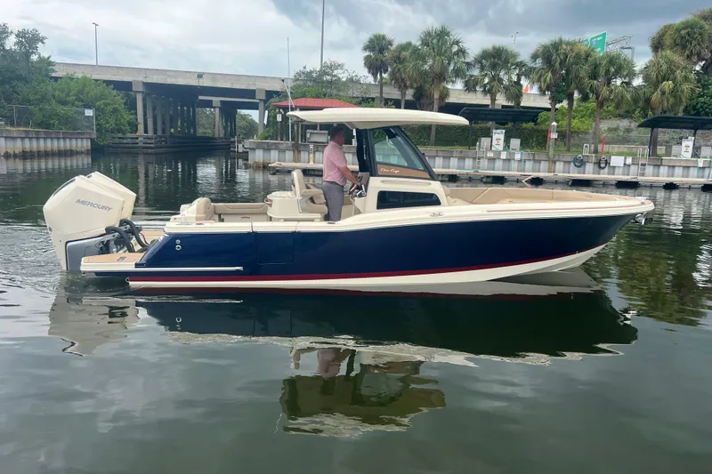 The Image of 2025 Chris-Craft Catalina 28 boat on calm water near a dock, featuring a Mercury engine. - 0