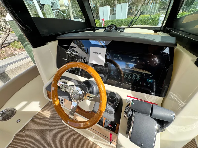 Slide: The Image of 2025 Chris-Craft Catalina 28 helm with wooden steering wheel and modern dashboard. - 18