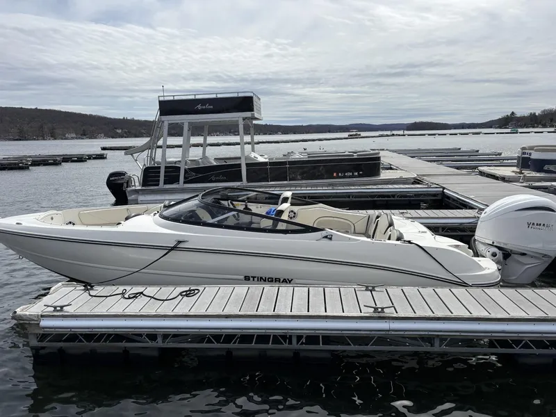 The Image of 2024 Stingray 23 OSX boat docked at a marina with scenic lake view. - 0