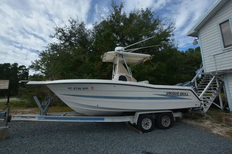 Slide: The Image of 1999 Hydra-Sports 2450 CCH boat on trailer, parked outdoors near trees and a building. - 1