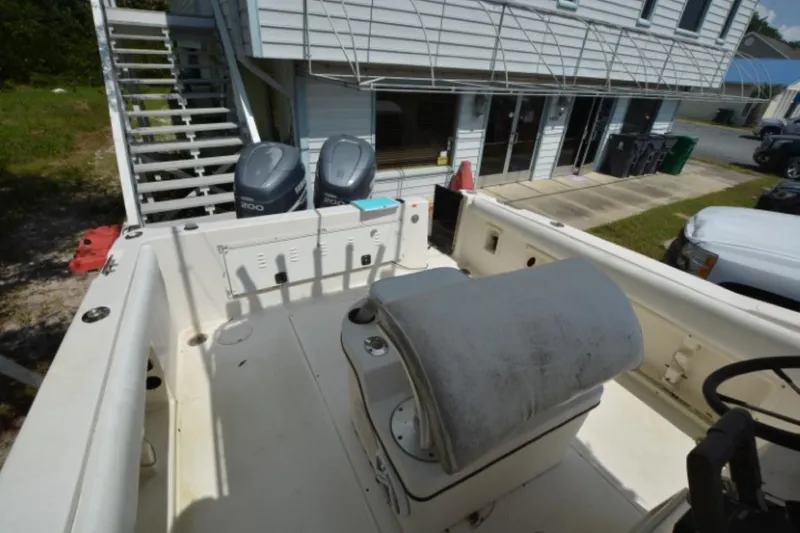 Slide: The Image of 1999 Hydra-Sports 2450 CCH boat interior with dual engines, parked near a building. - 14