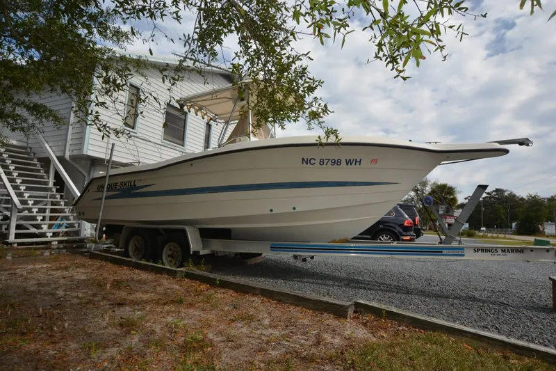 Slide: The Image of 1999 Hydra-Sports 2450 CCH boat on trailer near house, parked on gravel. - 2