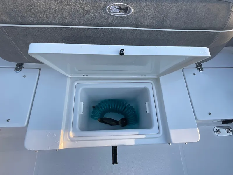 Slide: The Image of 2024 Sea Hunt Ultra 265 SE boat storage compartment with coiled hose. - 19