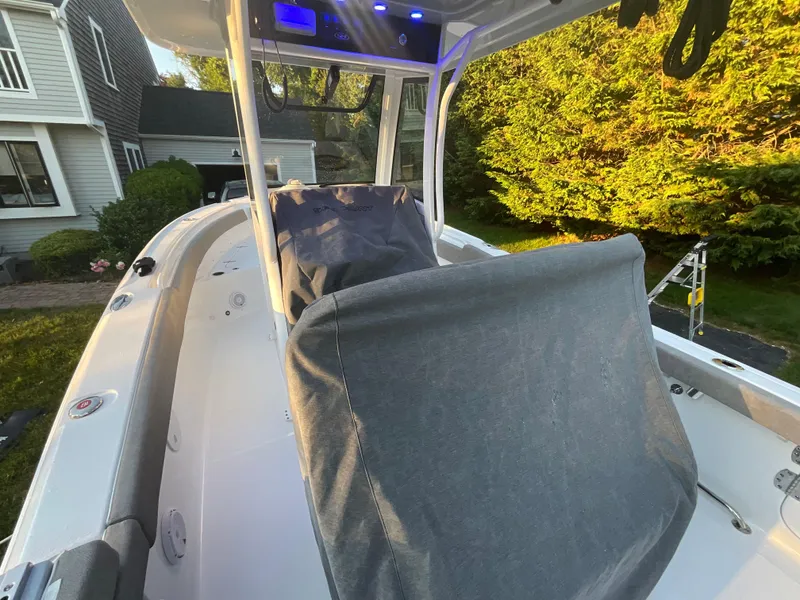 Slide: The Image of 2024 Sea Hunt Ultra 265 SE boat with covered seats, docked near a house and trees. - 23