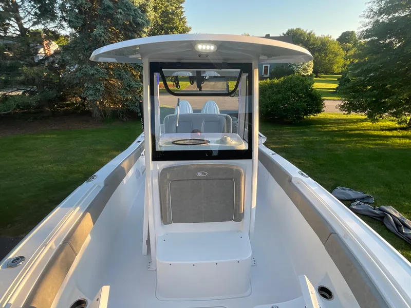 Slide: The Image of 2024 Sea Hunt Ultra 265 SE boat with center console and seating, parked on grass. - 5