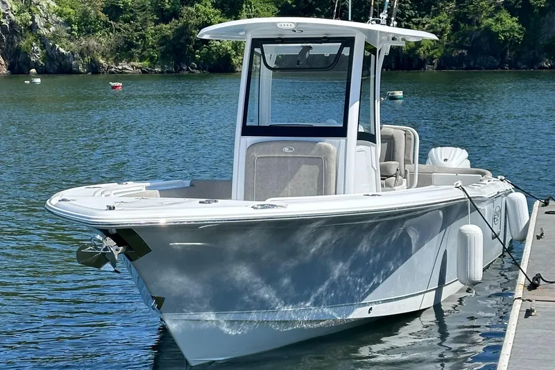 Slide: The Image of 2024 Sea Hunt Ultra 265 SE boat docked on a serene lake. - 7