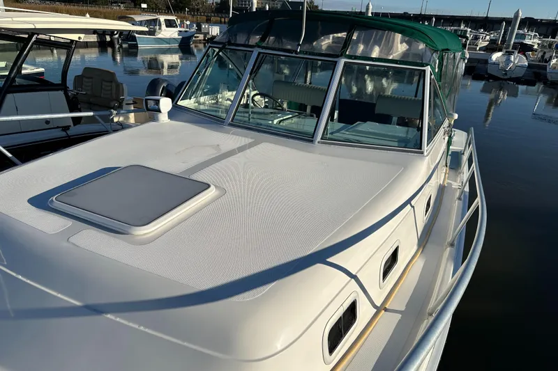 Slide: The Image of 2001 Mainship Pilot 30 boat docked in marina, featuring sleek design and green canopy. - 10