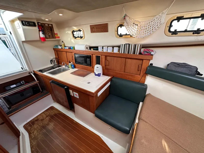 Slide: The Image of 2001 Mainship Pilot 30 interior with kitchenette, seating, and storage. Cozy and functional boat cabin. - 17