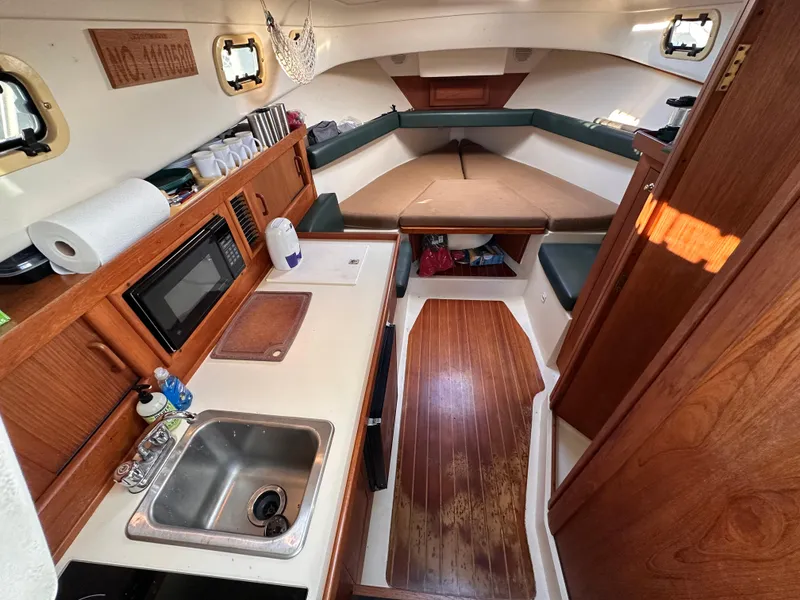 Slide: The Image of 2001 Mainship Pilot 30 interior with kitchenette, sink, and cozy seating area. - 18