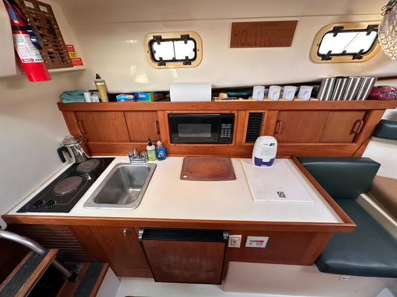 Slide: The Image of 2001 Mainship Pilot 30 boat kitchen with sink, stove, microwave, and storage cabinets. - 20