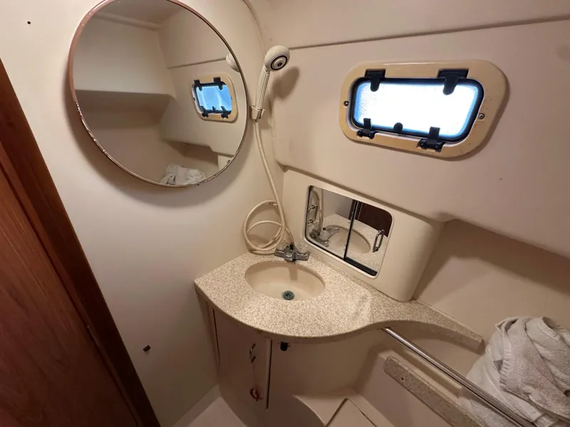 Slide: The Image of 2001 Mainship Pilot 30 bathroom with round mirror, sink, and porthole window. - 23