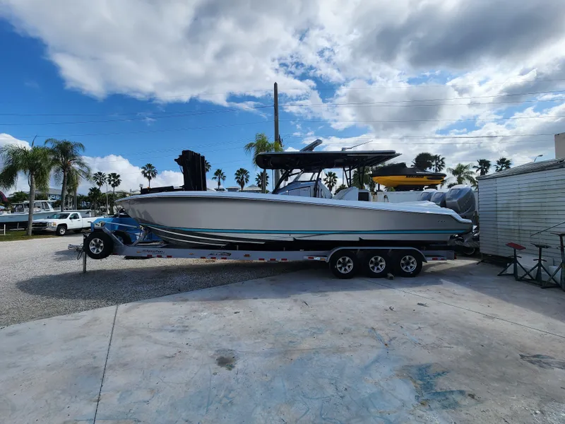 Slide: The Image of 2023 Nor-Tech 340 Sport Center Console boat on trailer under cloudy sky. - 2