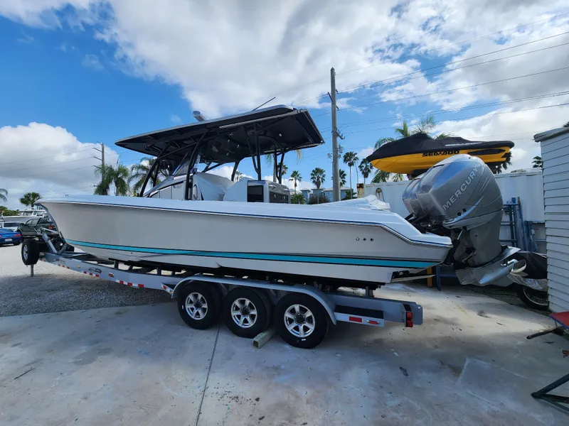 Slide: The Image of 2023 Nor-Tech 340 Sport Center Console boat on trailer, featuring triple outboard engines. - 3