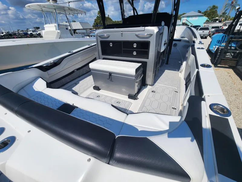 Slide: The Image of 2023 Nor-Tech 340 Sport Center Console boat interior with seating and storage, under a clear blue sky. - 9