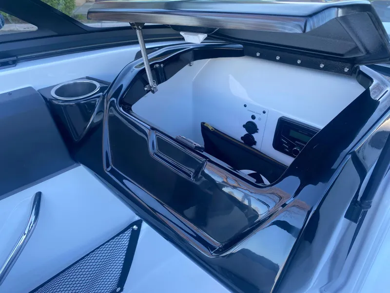 Slide: The Image of 2025 Scarab 195 SE boat interior storage compartment with open lid and cup holder. - 19