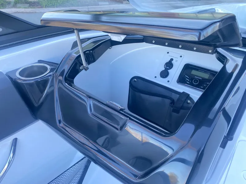 Slide: The Image of 2025 Scarab 215 SE boat dashboard with open storage compartment and control panel. - 15