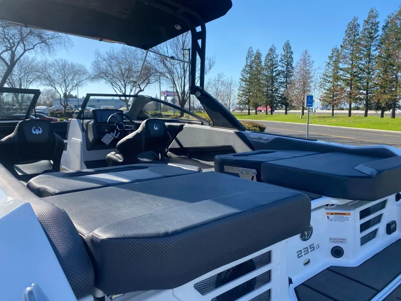 Slide: The Image of 2025 Scarab 235 LX Wake boat interior with seating, parked outdoors. - 24