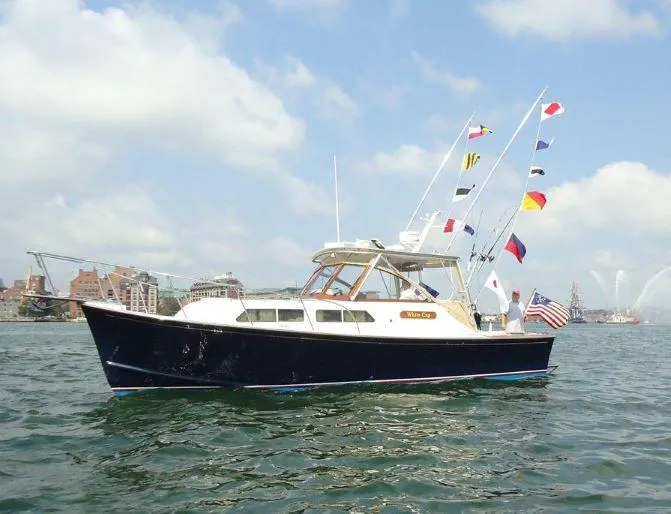 Slide: The Image of 1997 Fortier 33 HT Express boat with flags on water, clear sky background. - 3