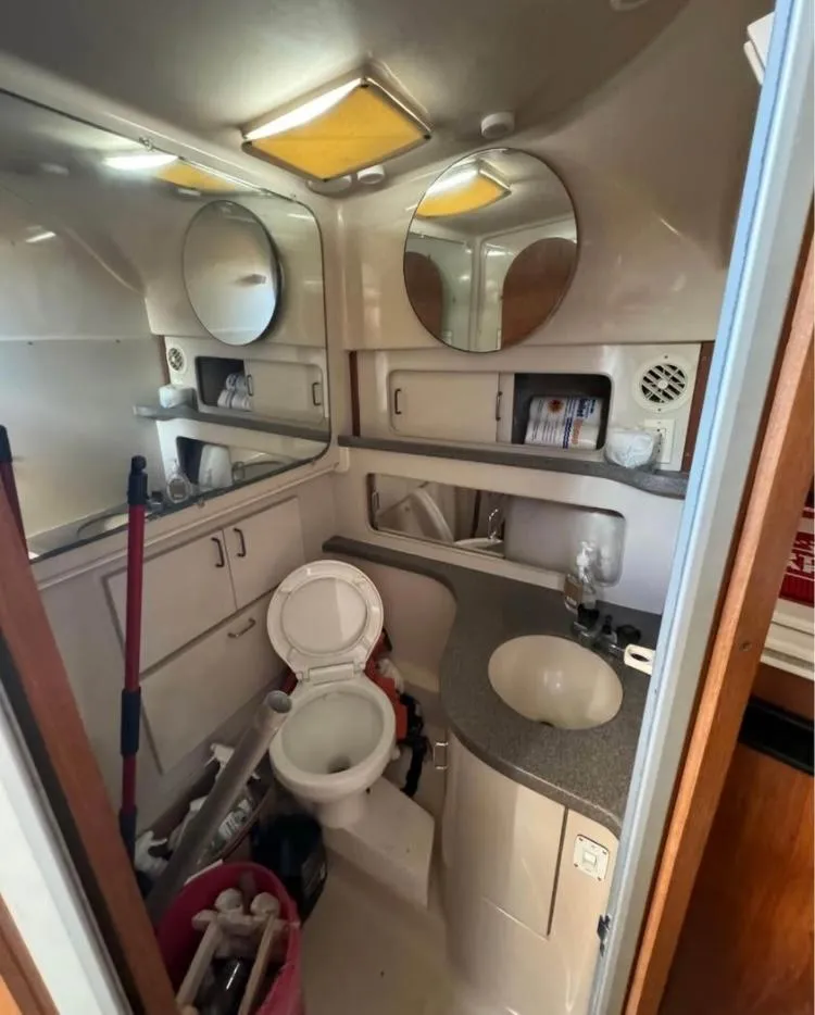 Slide: The Image of 1996 Luhrs Tournament 320 Open boat bathroom with sink, toilet, and storage shelves. - 8