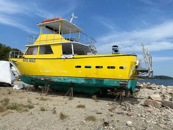 Slide: The Image of Yellow 1978 Marine Management Flybridge boat on rocky shore under blue sky. - 3