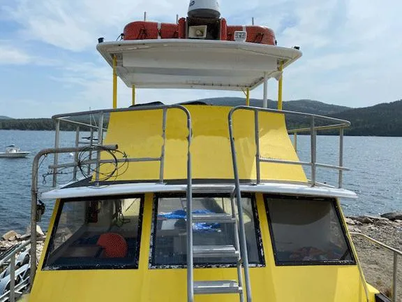 Slide: The Image of Yellow 1978 Marine Management Flybridge Commercial Passenger boat docked by a lake. - 4