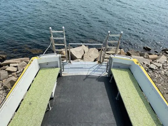 Slide: The Image of 1978 Marine Management Flybridge boat with seating, docked by rocky shoreline. - 6