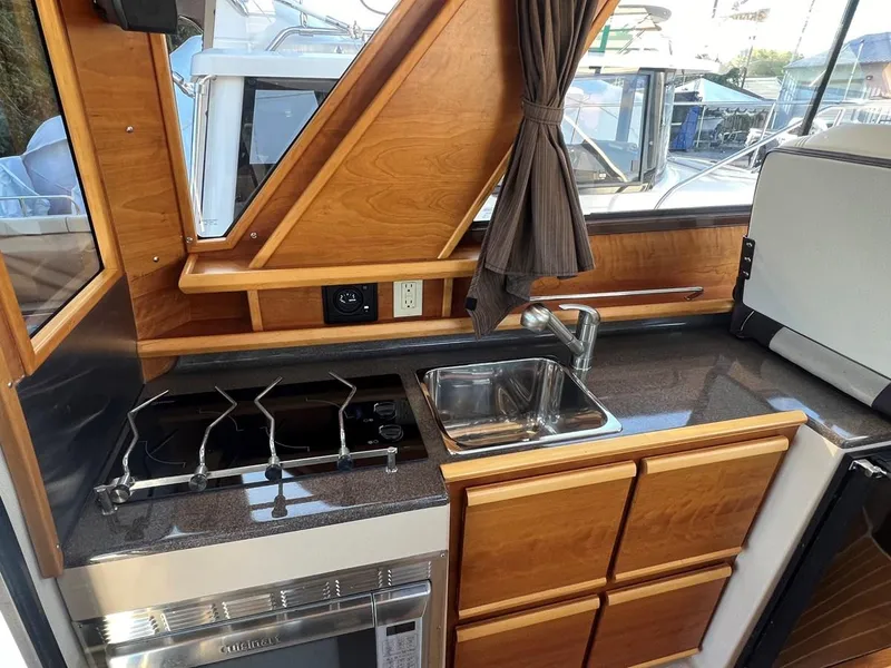Slide: The Image of 2016 Cutwater C-28 boat kitchen with stove, sink, and wooden cabinetry. - 35