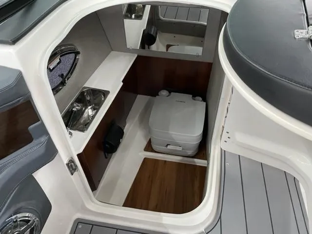 Slide: The Image of 2021 Chaparral 267 SSX OB boat interior with compact bathroom and sink. - 11