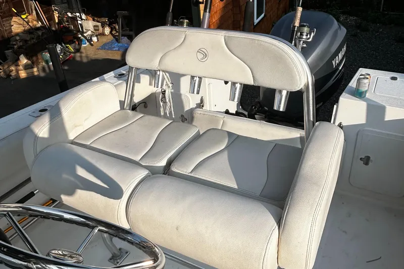 Slide: The Image of Edgewater 228CC 2010 boat interior with cushioned seating and steering wheel. - 12
