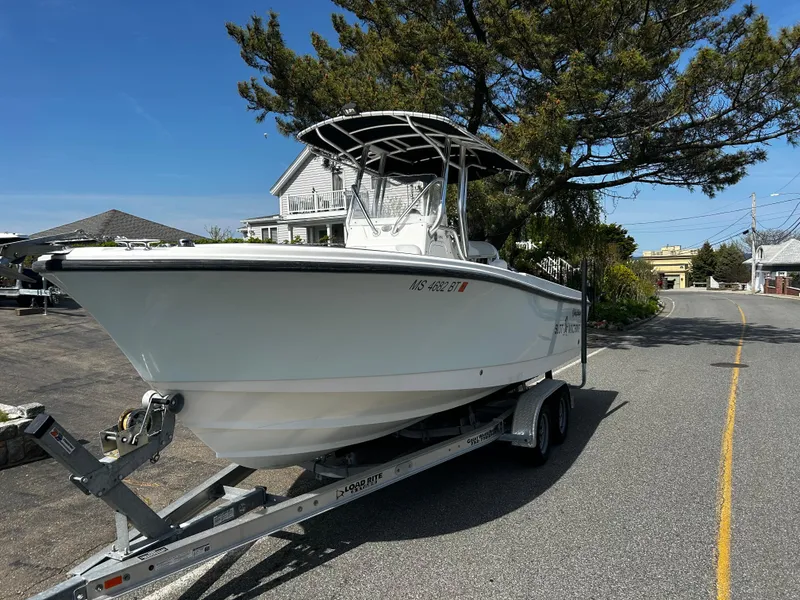 Slide: The Image of 2010 Edgewater 228CC boat on trailer, parked on a sunny street. - 2