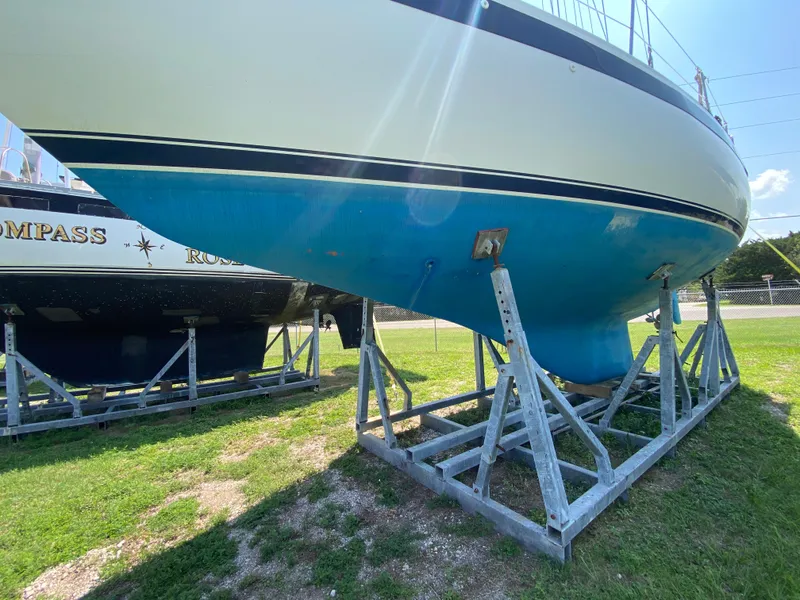 Slide: The Image of 1972 Ericson 39 Flushdeck sailboat on stands, blue hull, grassy yard. - 11