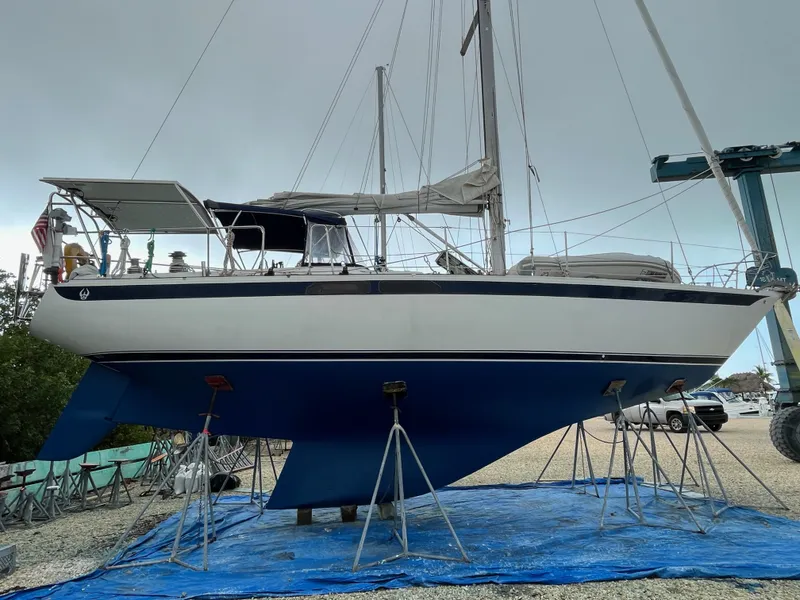 Slide: The Image of 1972 Ericson 39 Flushdeck sailboat on stands, blue hull, covered deck, overcast sky. - 7