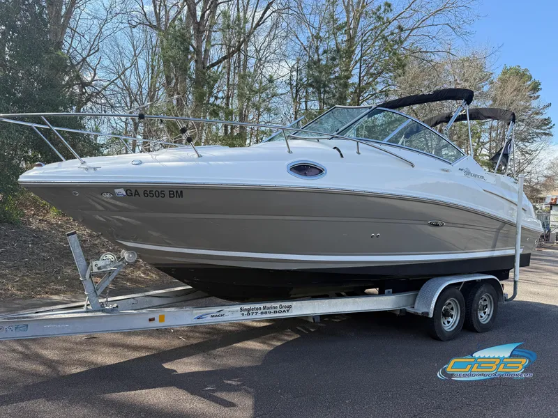 The Image of 2007 Sea Ray 240 Sundancer boat on trailer, parked outdoors, surrounded by trees. - 0