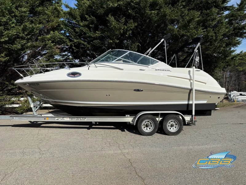Slide: The Image of 2007 Sea Ray 240 Sundancer boat on trailer, parked outdoors with trees in background. - 2