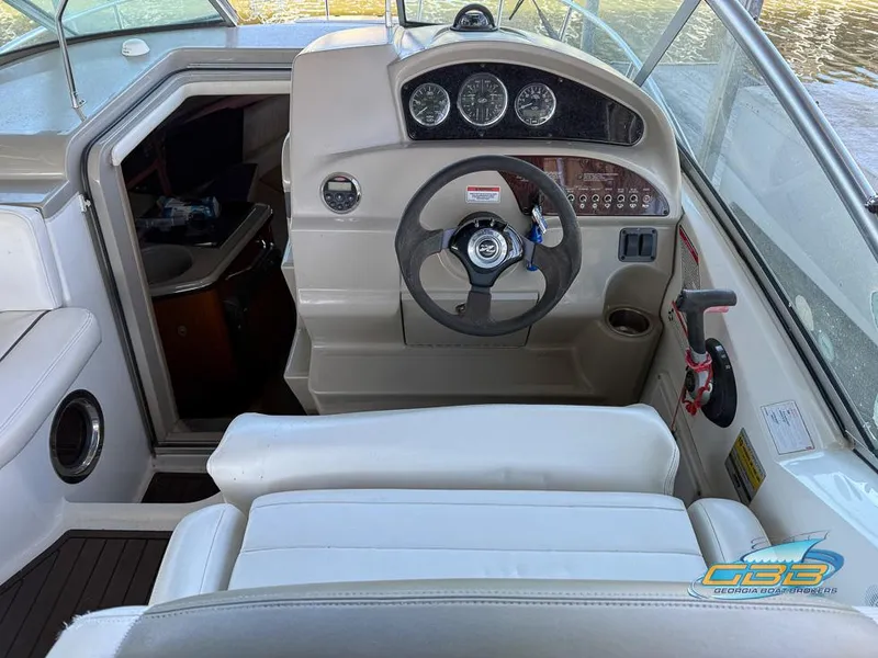 Slide: The Image of 2007 Sea Ray 240 Sundancer helm with steering wheel and gauges, featuring white seating. - 26