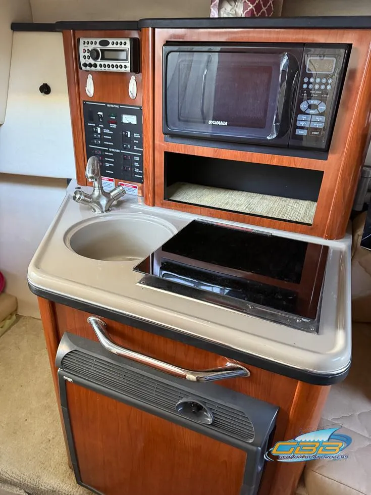 Slide: The Image of 2007 Sea Ray 240 Sundancer kitchenette with microwave, sink, and stove. - 28