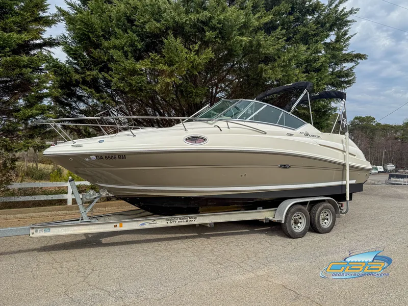 Slide: The Image of 2007 Sea Ray 240 Sundancer boat on trailer, parked outdoors with trees in background. - 4