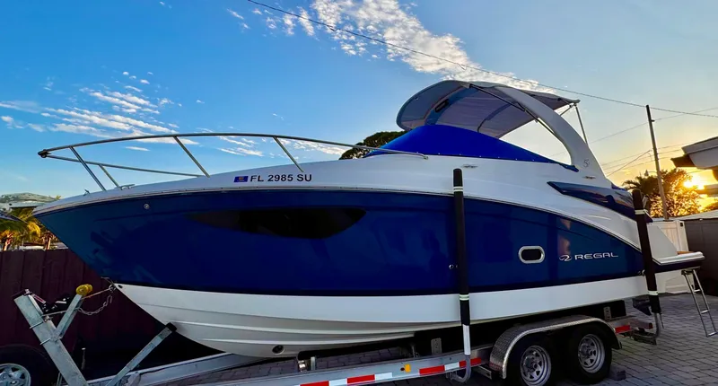 Slide: The Image of 2020 Regal 26XO boat on trailer under a clear blue sky. - 2