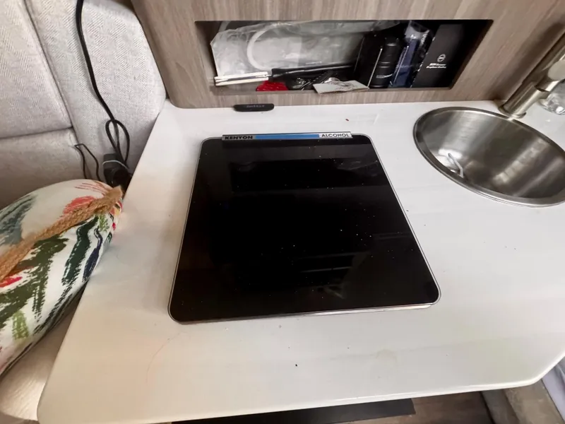 Slide: The Image of Compact kitchen area in a 2020 Regal 26XO boat with a sleek induction cooktop. - 50