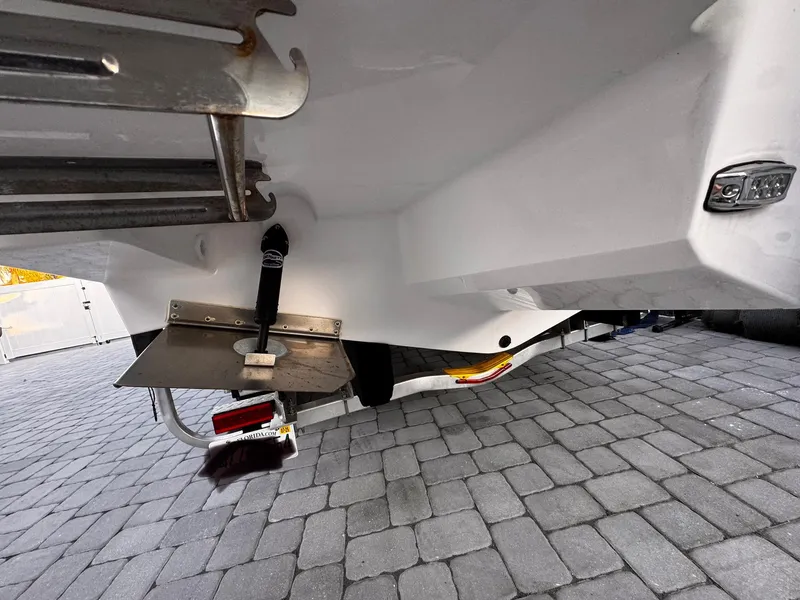 Slide: The Image of 2020 Regal 26XO boat underside with trim tab and ladder on paved surface. - 82
