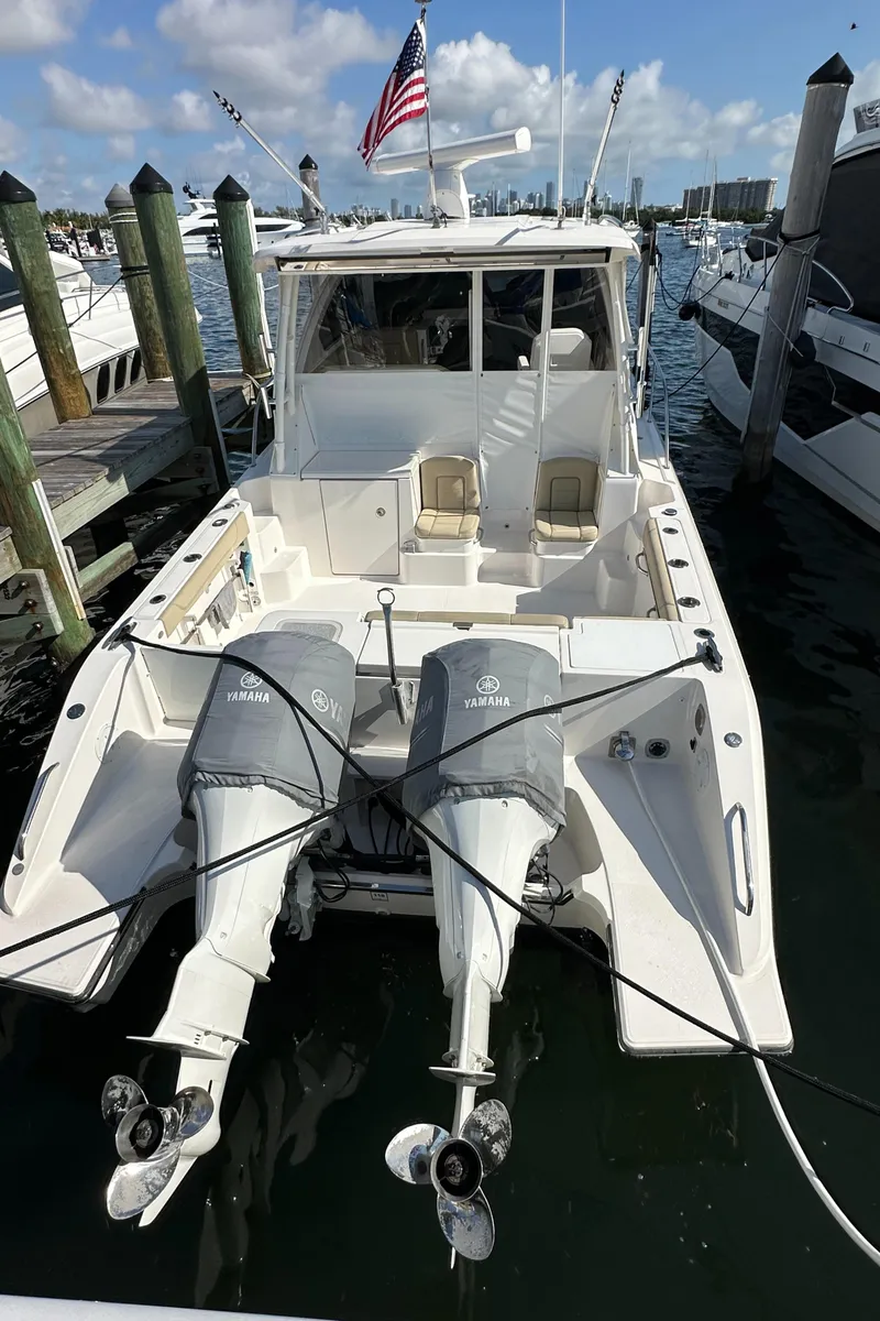 Slide: The Image of 2017 Pursuit OS 355 Offshore boat docked, featuring dual outboard engines and an American flag. - 1
