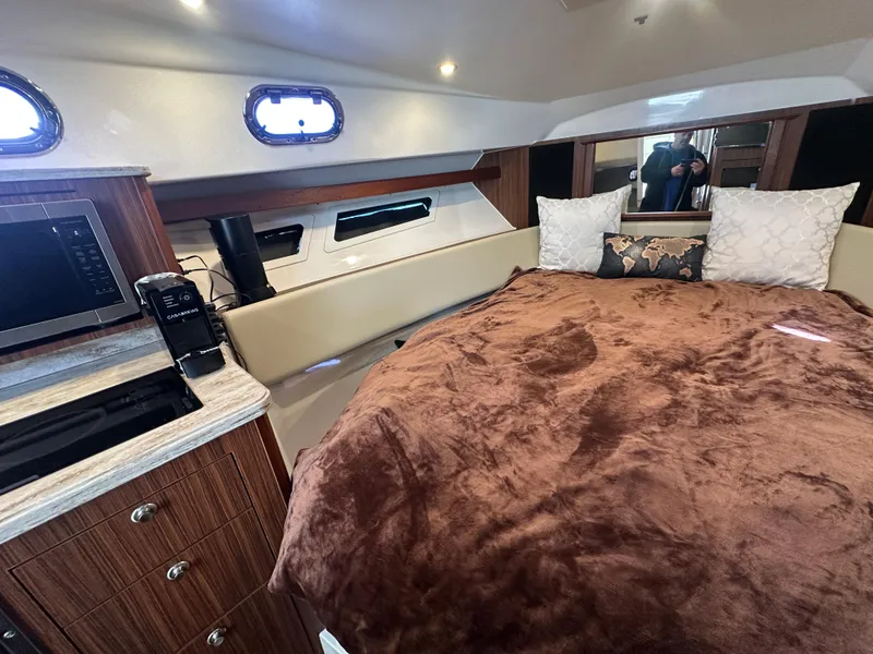 Slide: The Image of 2017 Pursuit OS 355 Offshore cabin with cozy bed, microwave, and wood cabinetry. - 20
