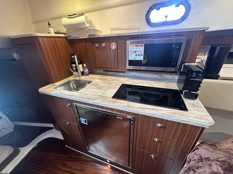 Slide: The Image of 2017 Pursuit OS 355 Offshore yacht kitchen with sink, stove, and microwave. - 23