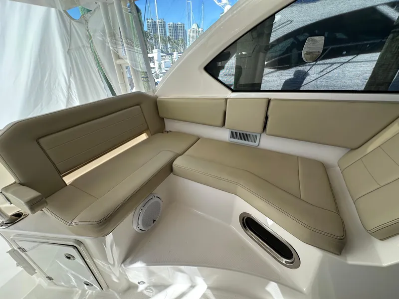 Slide: The Image of 2017 Pursuit OS 355 Offshore boat interior with beige seating and window view. - 25